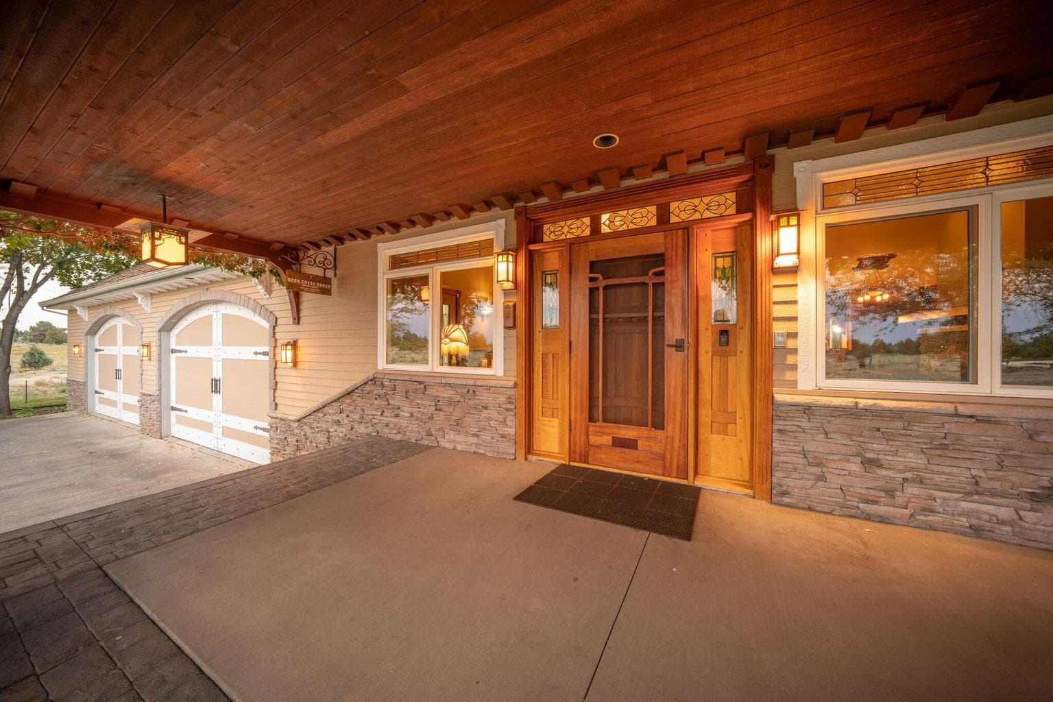 Front entryway door is Brazilian cherry w/African mahogany screen doors in the Green & Green style. Handmade stained glass and copper light fixtures at night. Large concrete covered porch and 4-car garage w/doors made to look like barn doors