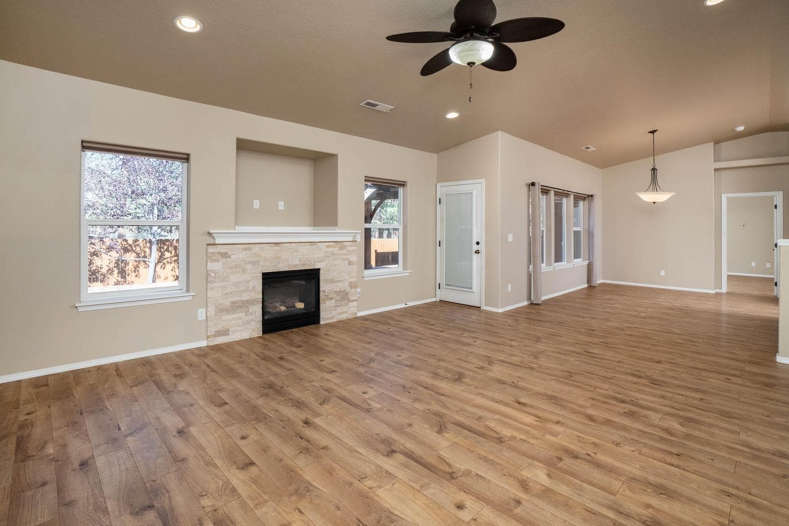 Great room with propane fireplace, vaulted, ceiling fan, nice window coverings, door to back deck.