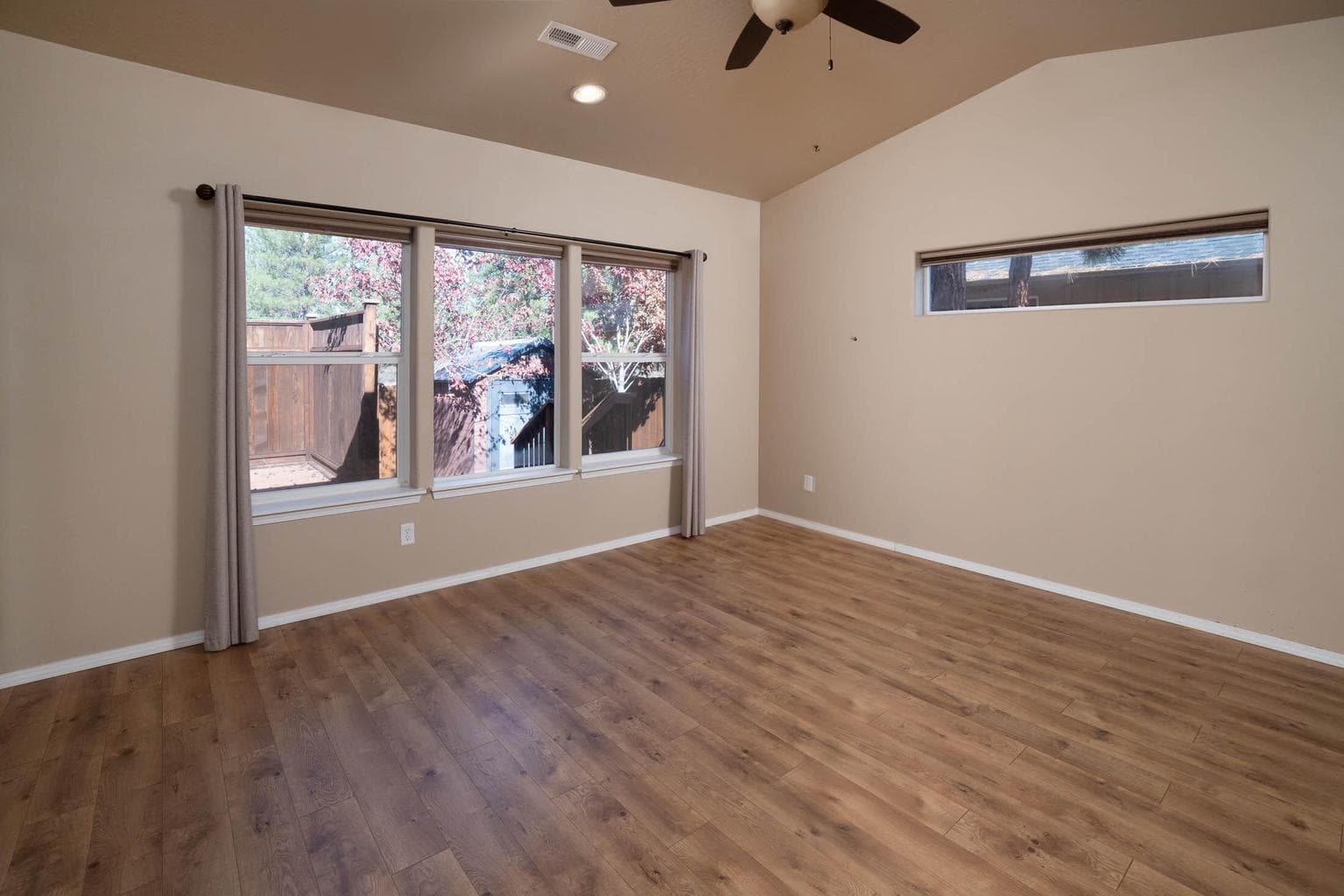Primary bedroom with windows and door to an expansive back deck, vaulted, ceiling fan