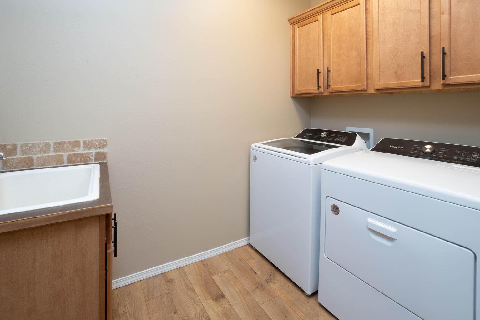 Laundry room with deep sink, washer, dryer and upper cabinets for supplies