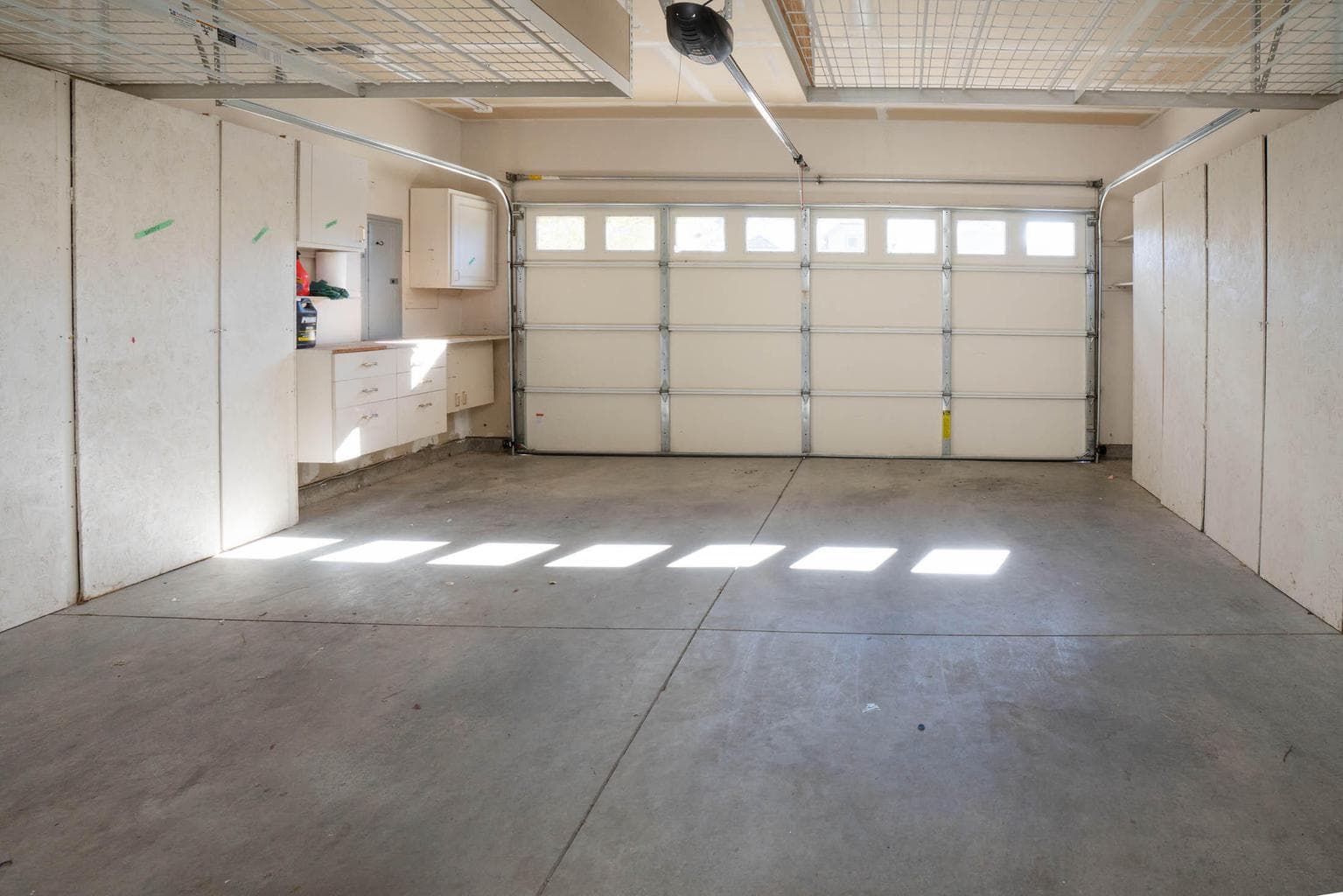 Large double car garage with opener, man door. workbench and ample storage