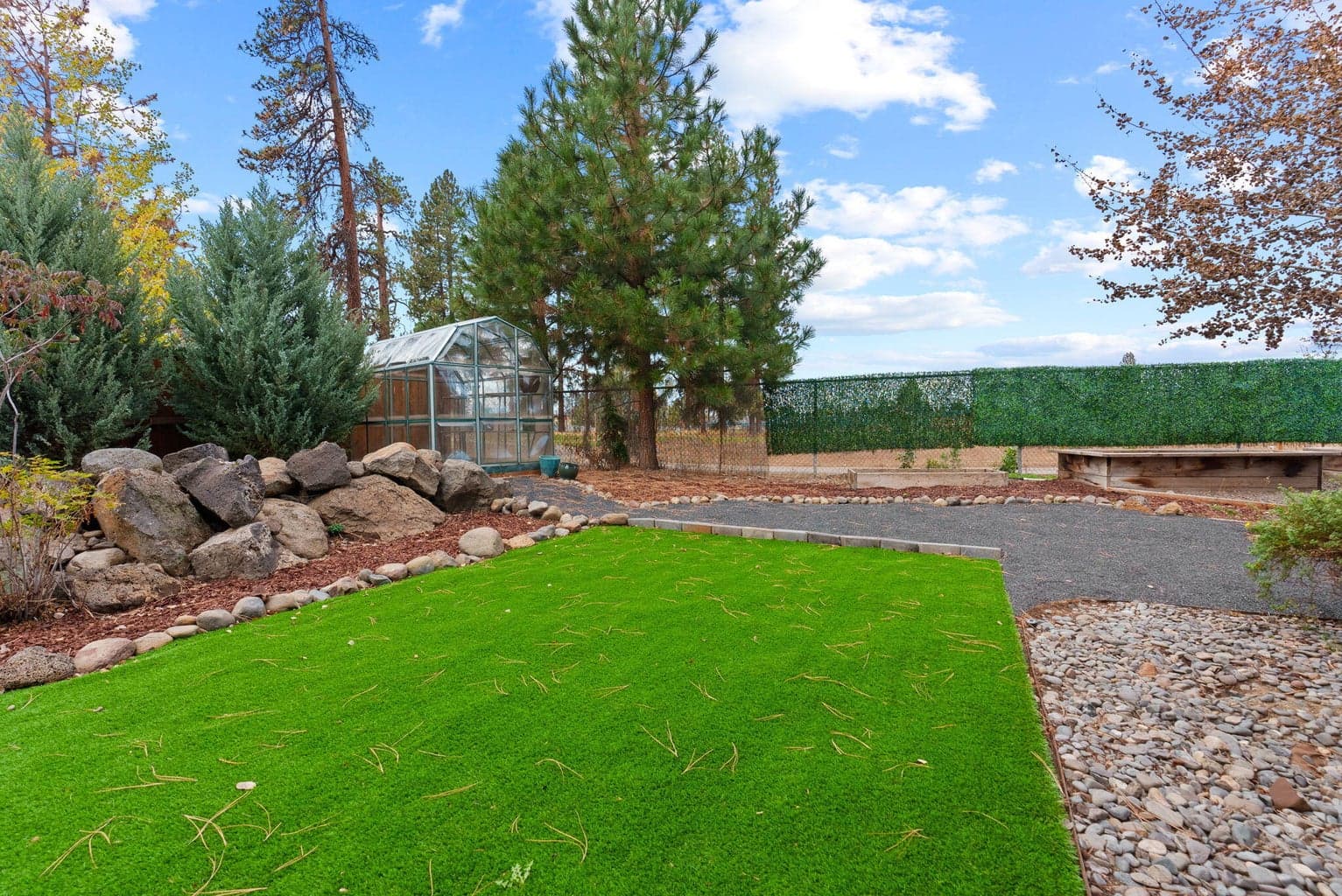Perfect for outdoor living and hobbies is the fenced yard featuring the 180 SF shed, separate greenhouse, raised garden beds with a drip system, and a covered patio.