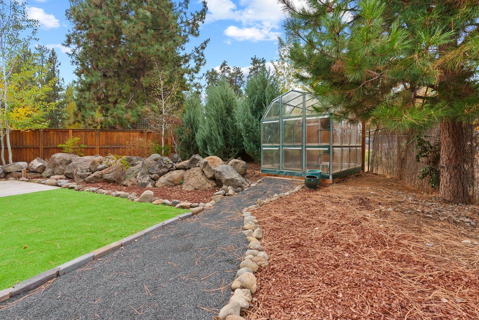 Perfect for outdoor living and hobbies is the fenced yard featuring the 180 SF shed, separate greenhouse, raised garden beds with a drip system, and a covered patio.