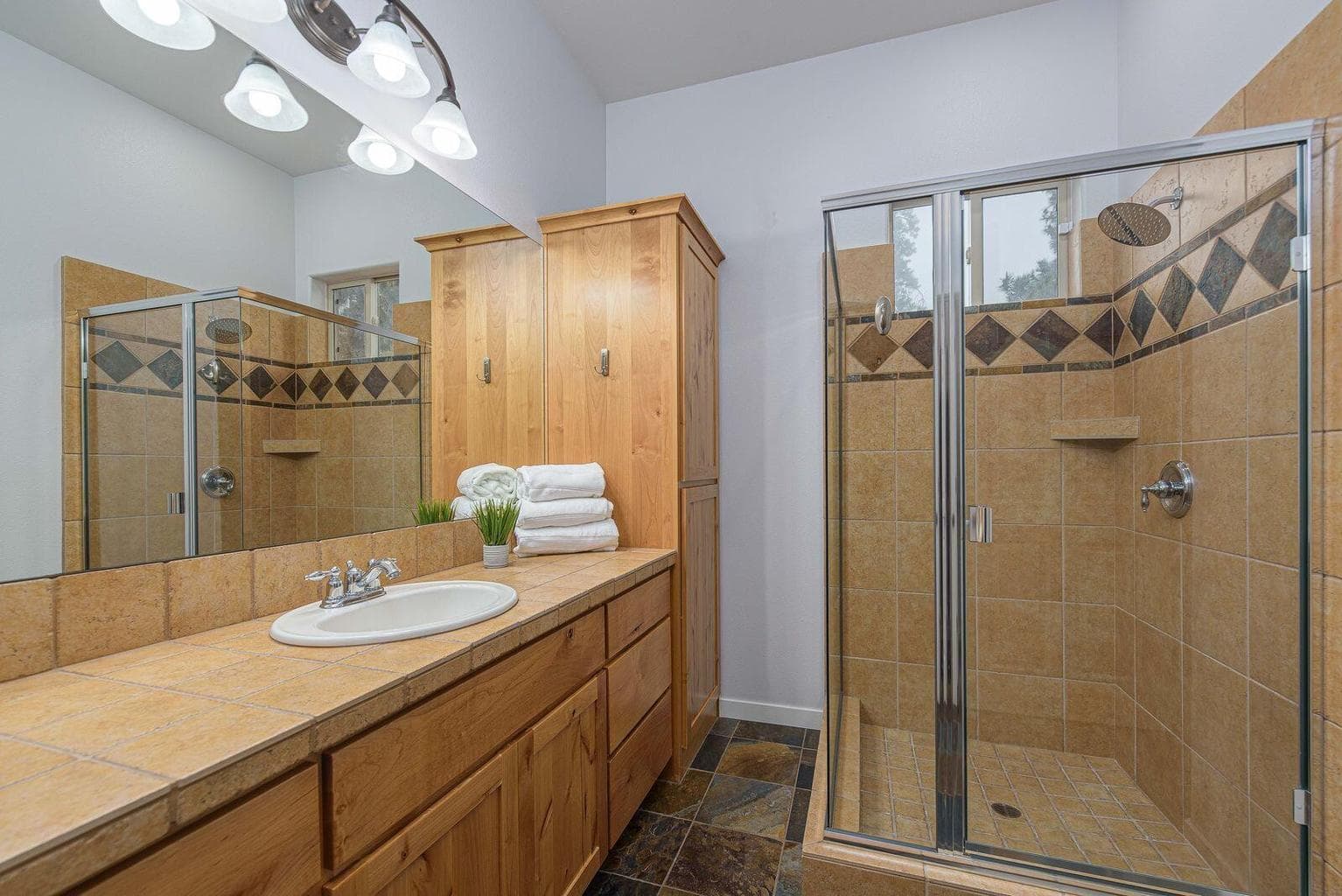 Walk in shower, dual sinks and an enclosed toilet area