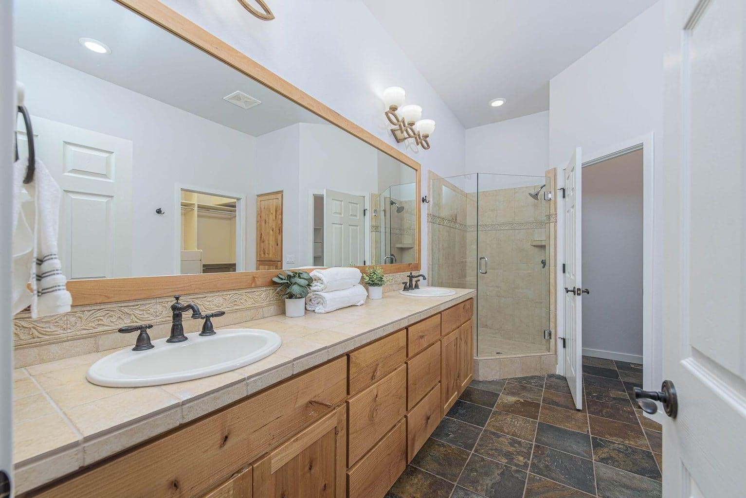 Primary bathroom with dual sinks, walk in shower, and lots of cabinetry