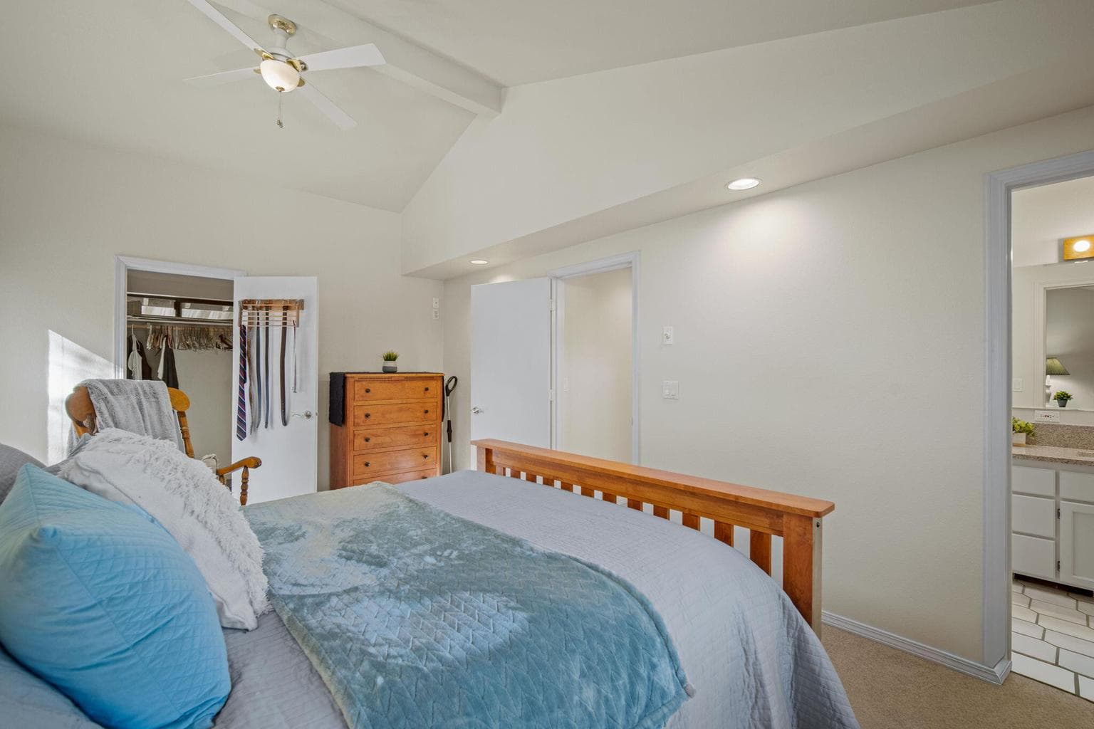 Vaulted ceiling in spacious primary suite and door to primary bathroom.