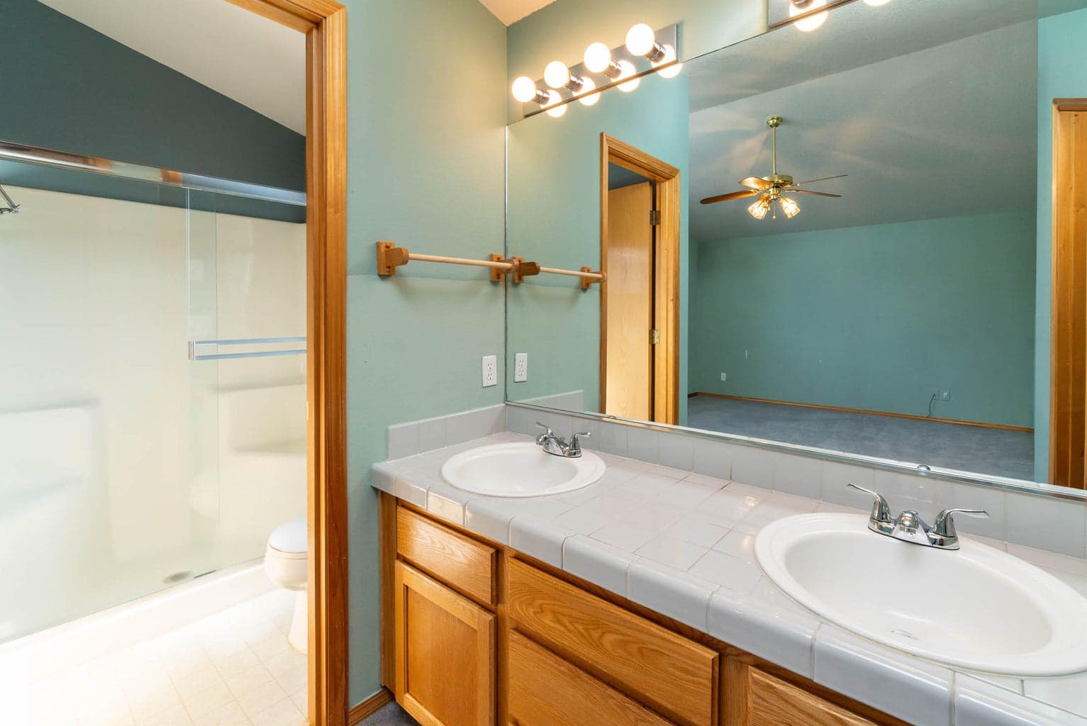 primary bathroom with double vanities, tile counters, separate shower & toilet