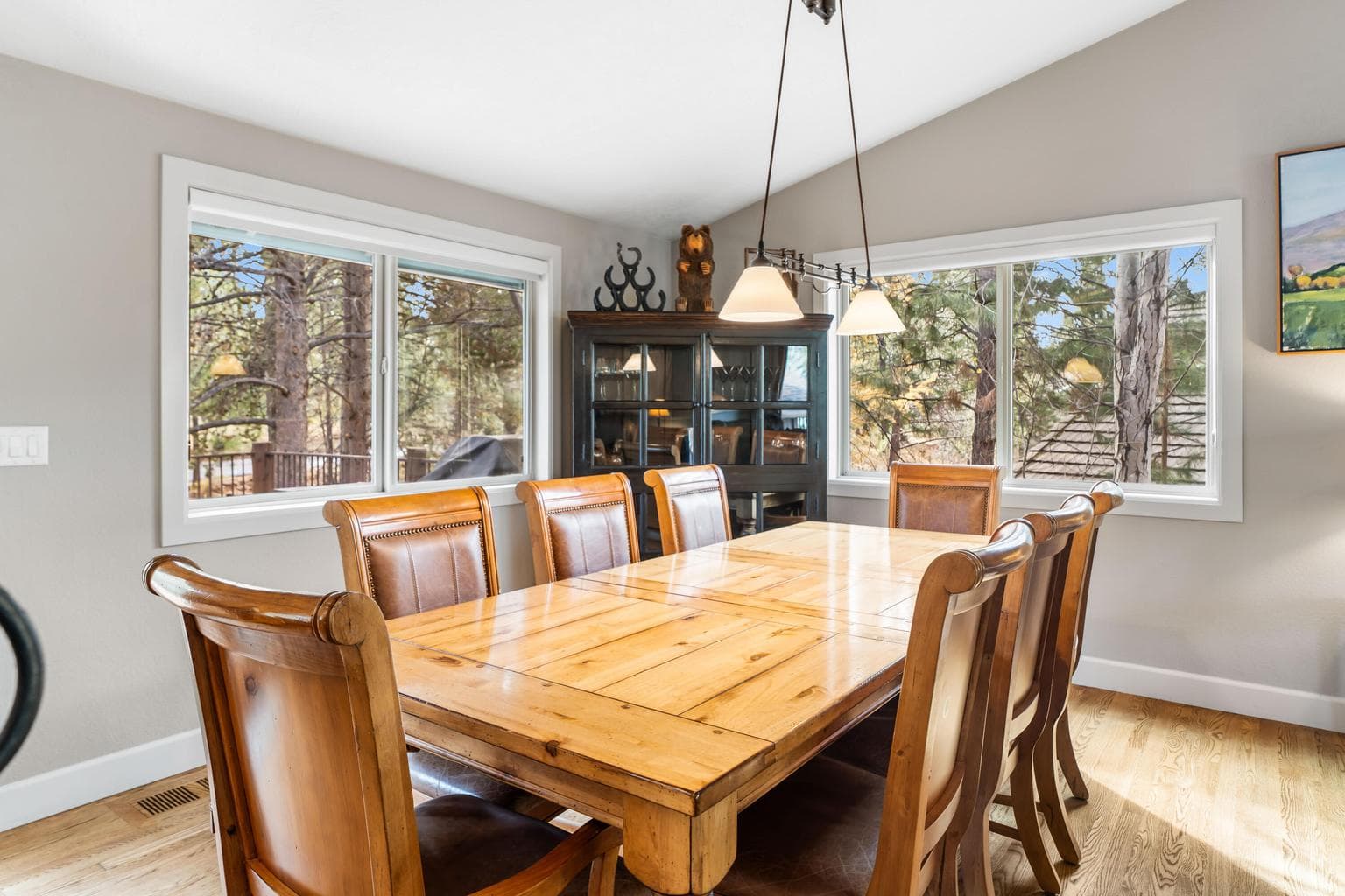 Surrounded by large windows, this inviting dining area captures natural light and peaceful woodland scenery. The warm wood tones and open layout create the perfect setting for family meals or gatherings with friends.