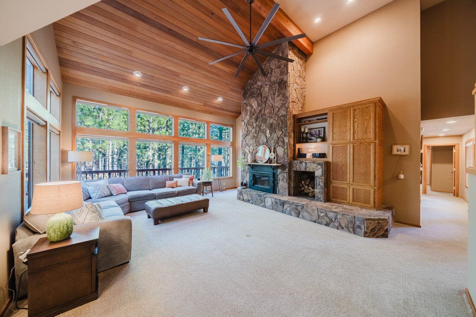 Vaulted living room with a majestic ceiling fan and a wood burning fireplace insert to make the house toasty warm in the colder months.