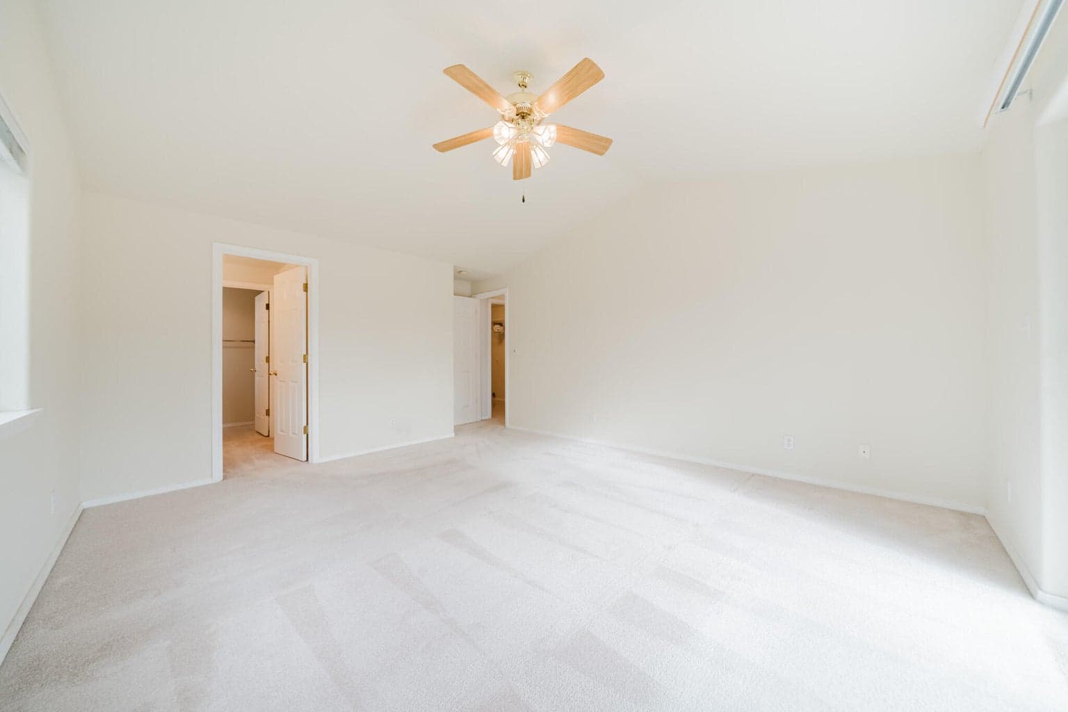 Primary Suite is on the opposite side of the house from the guest bedrooms. Vaulted ceiling with a fan make it cozy.