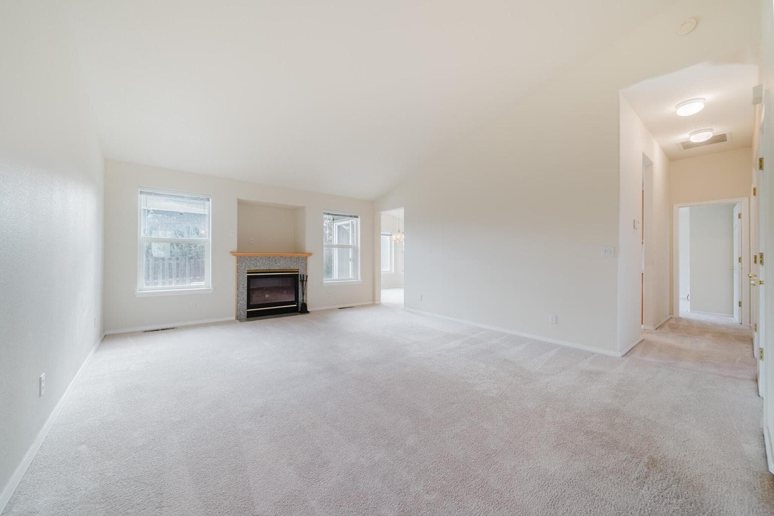 Living Room with view down hall with laundry room and garage access, kitchen access, and primary suite, and entrance to the dining room at the back of the house.
