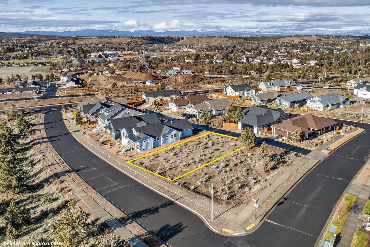 Distant view of surrounding homes and mountain vistas beyond the lot.