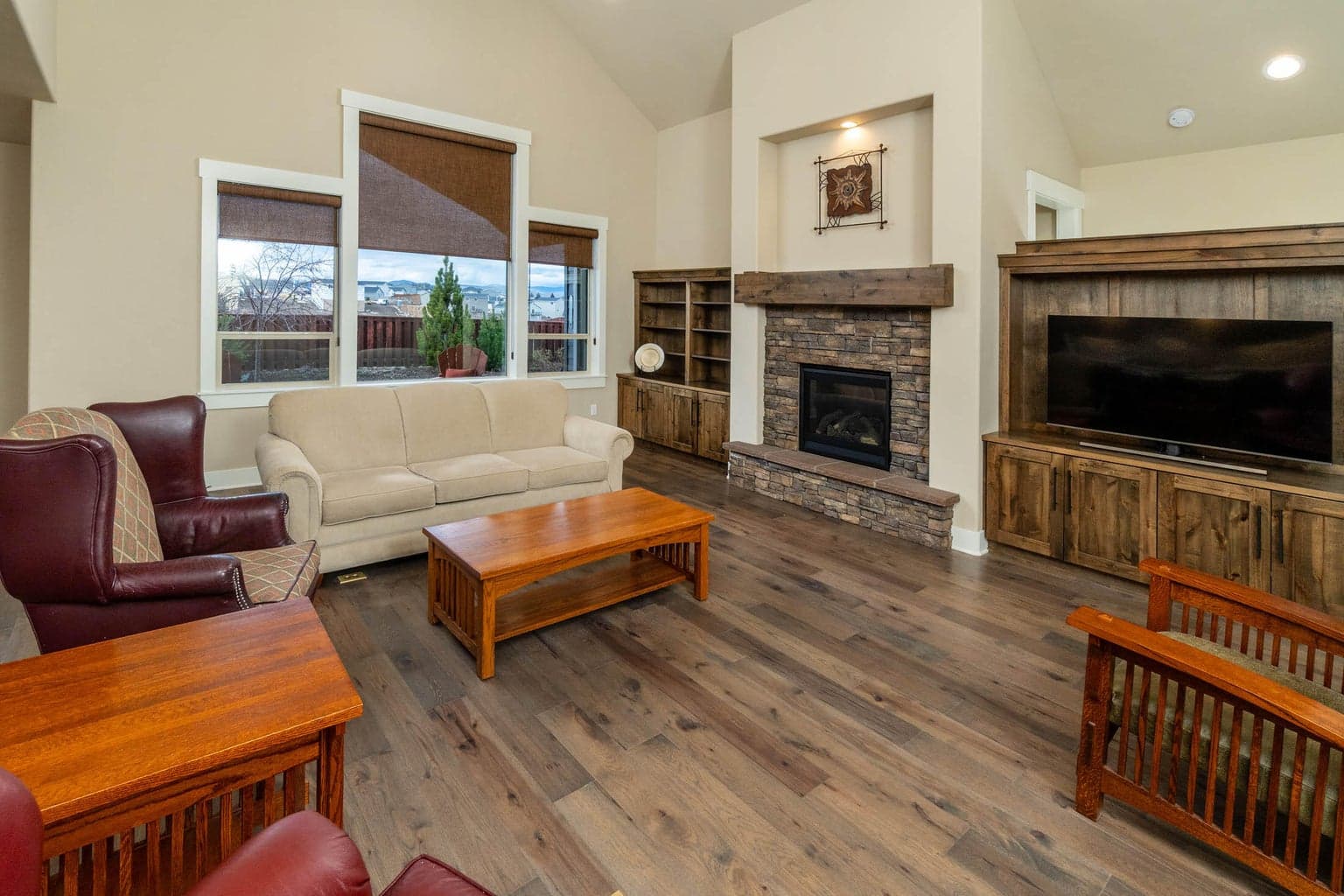 Gas fireplace has hearth and stained mantle. Built-in matching shelves on the sides of the fireplace. Wood wrapped windows.