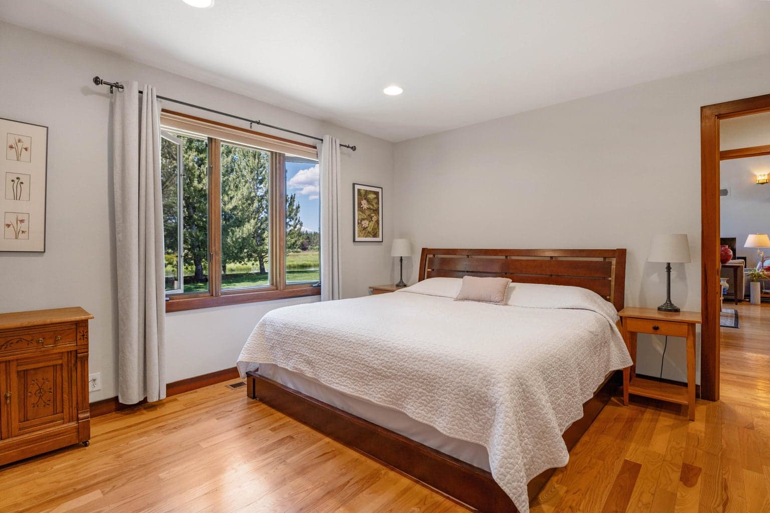 Bedroom with windows showcasing the outside lawn, river and mountains