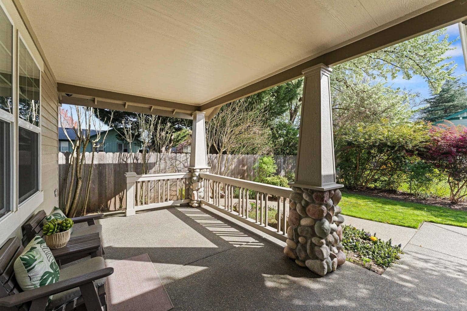 Front covered Poarch overlooking lush mature landscape.