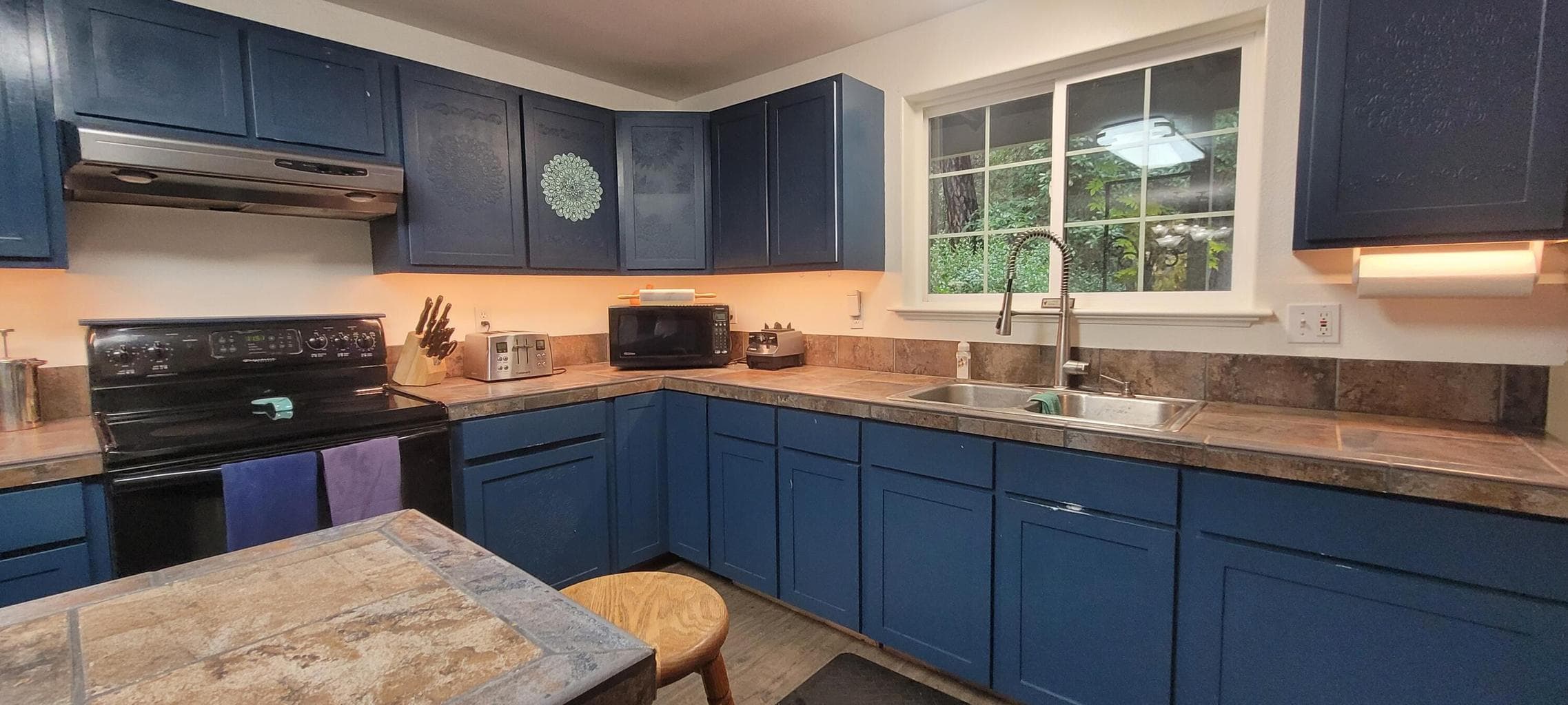 Tile island, tile counters, and motion sensor lights in the corner cabinets. Lots of storage throughout. Not pictured, Huge pantry with a rack on wheels to keep items from getting lost in the back.