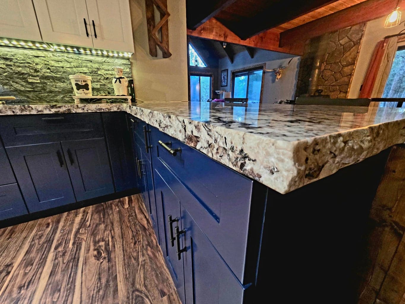 Extra depth live edge on granite countertops. White cabinets above and navy blue below.
