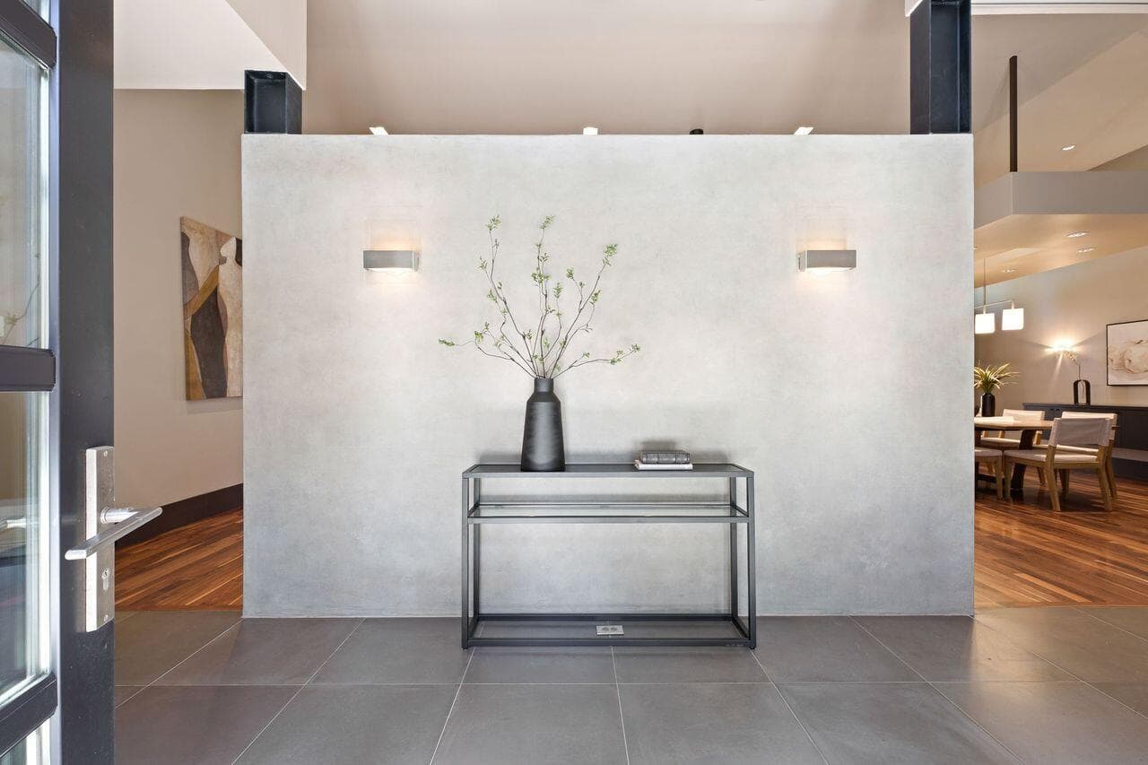 Entry interior featuring a custom concrete-finished wall that creates a striking architectural moment while offering privacy and separation from the main living spaces. The design maintains a sense of openness and light, with clean lines, warm materials, and a cohesive palette that sets the tone for the home’s modern, thoughtfully curated aesthetic.