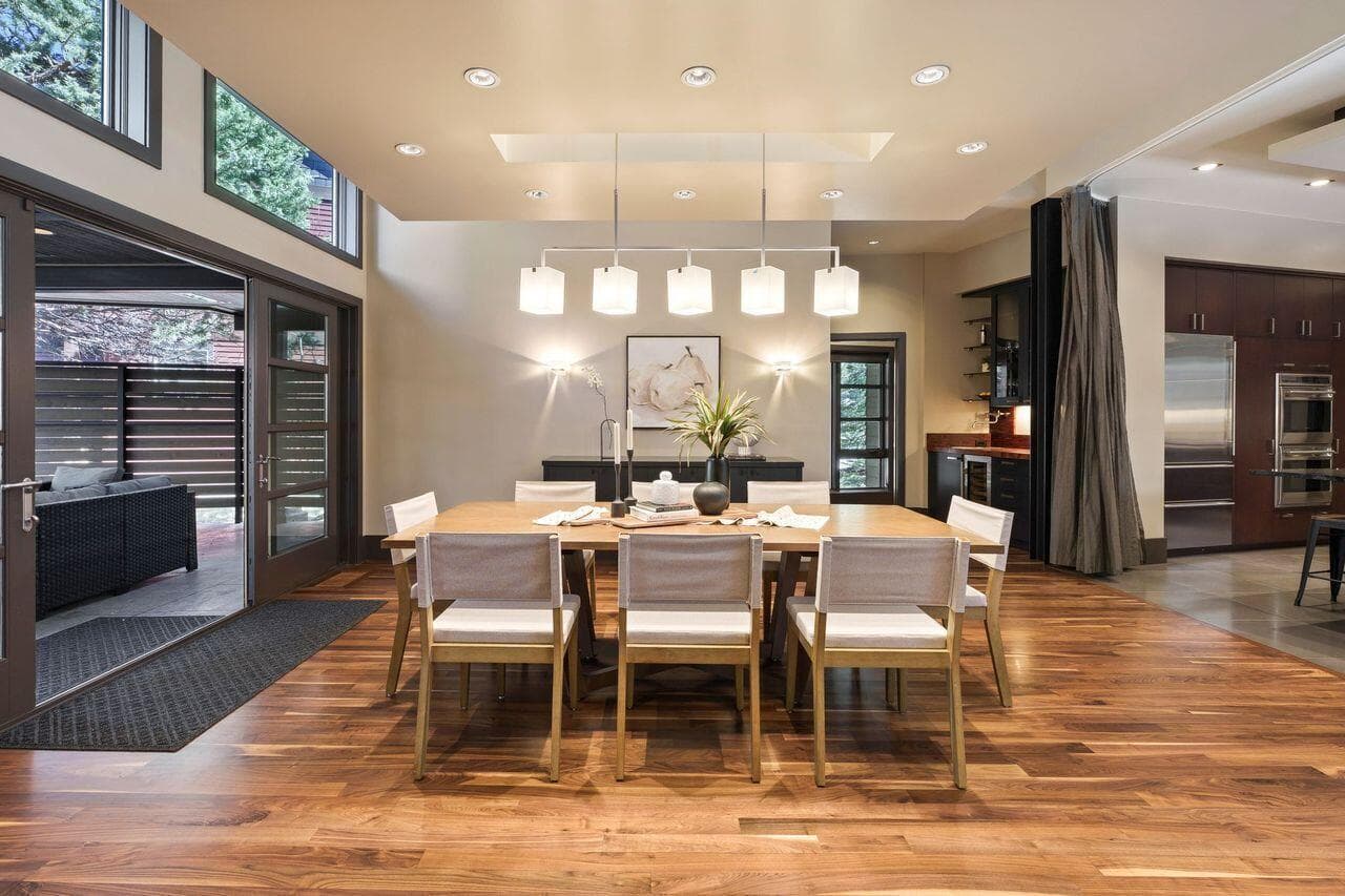 Dining space with warm walnut flooring, modern lighting, and easy access to both the kitchen and outdoor patio, creating a natural flow for everyday living and entertaining.