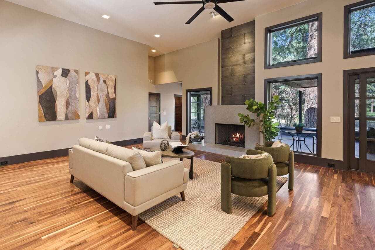 Living area with soaring ceilings, a modern fireplace, and expansive windows that frame the surrounding pines, creating a warm and inviting space with a strong connection to the outdoors.