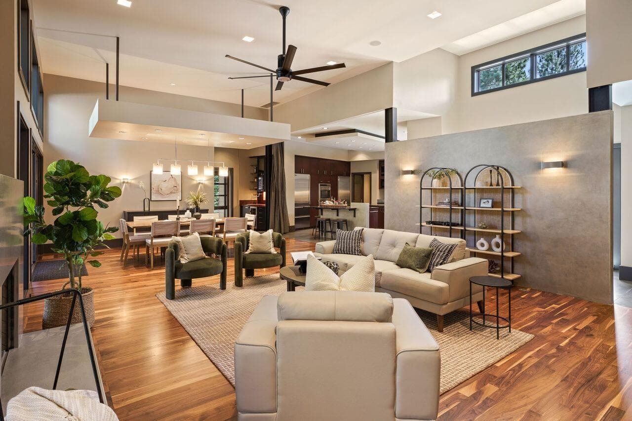 Open-concept living and dining spaces connected by warm walnut flooring and clean architectural lines, with a custom concrete feature wall adding both definition and visual interest. The layout offers a natural flow between spaces while maintaining a sense of separation for comfortable, everyday living.