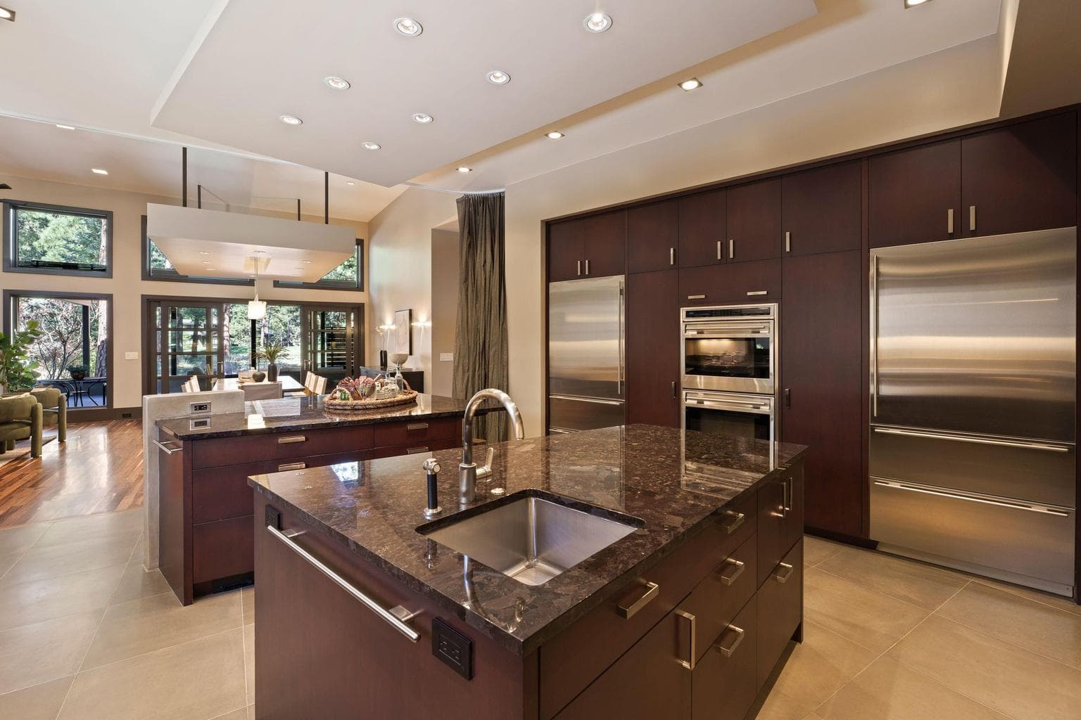 Kitchen with dual trapezoidal islands—one for prep, one for gathering—plus a hidden pantry and seamless connection to dining and living spaces.