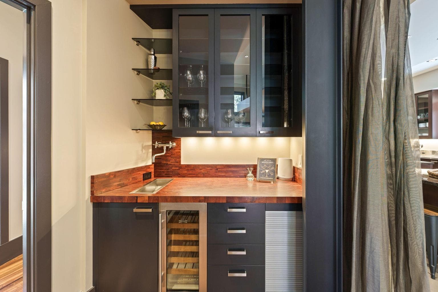 Just off the kitchen, a built-in bar with sink, and warm wood accents adds a thoughtful layer for entertaining.