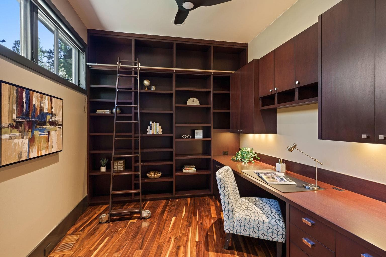 Dedicated office just off the kitchen with custom built-ins and library ladder, creating a warm and functional workspace.