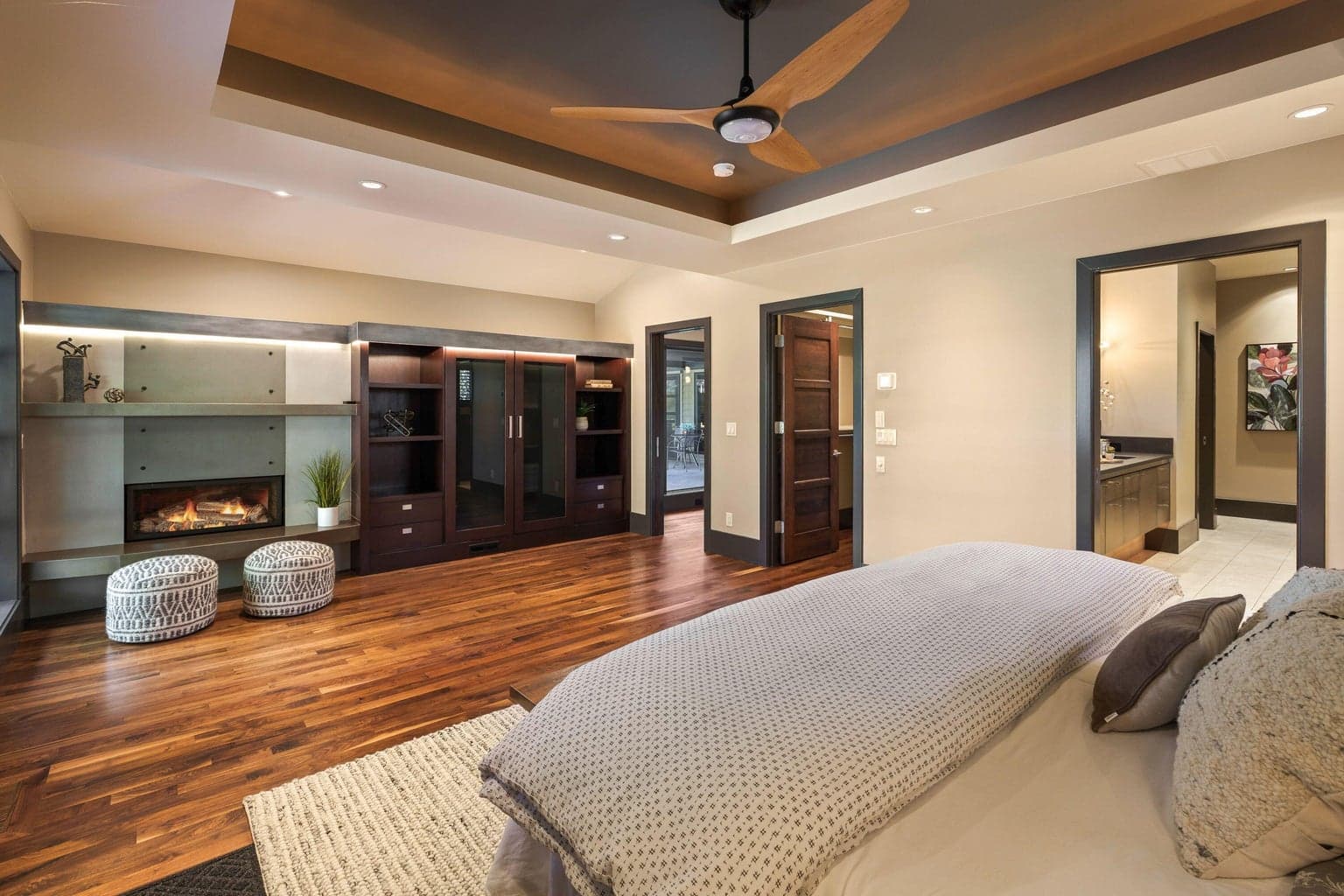 Spacious primary suite with tray ceiling detail, built-in cabinetry, fireplace, and seamless connection to the ensuite bath.
