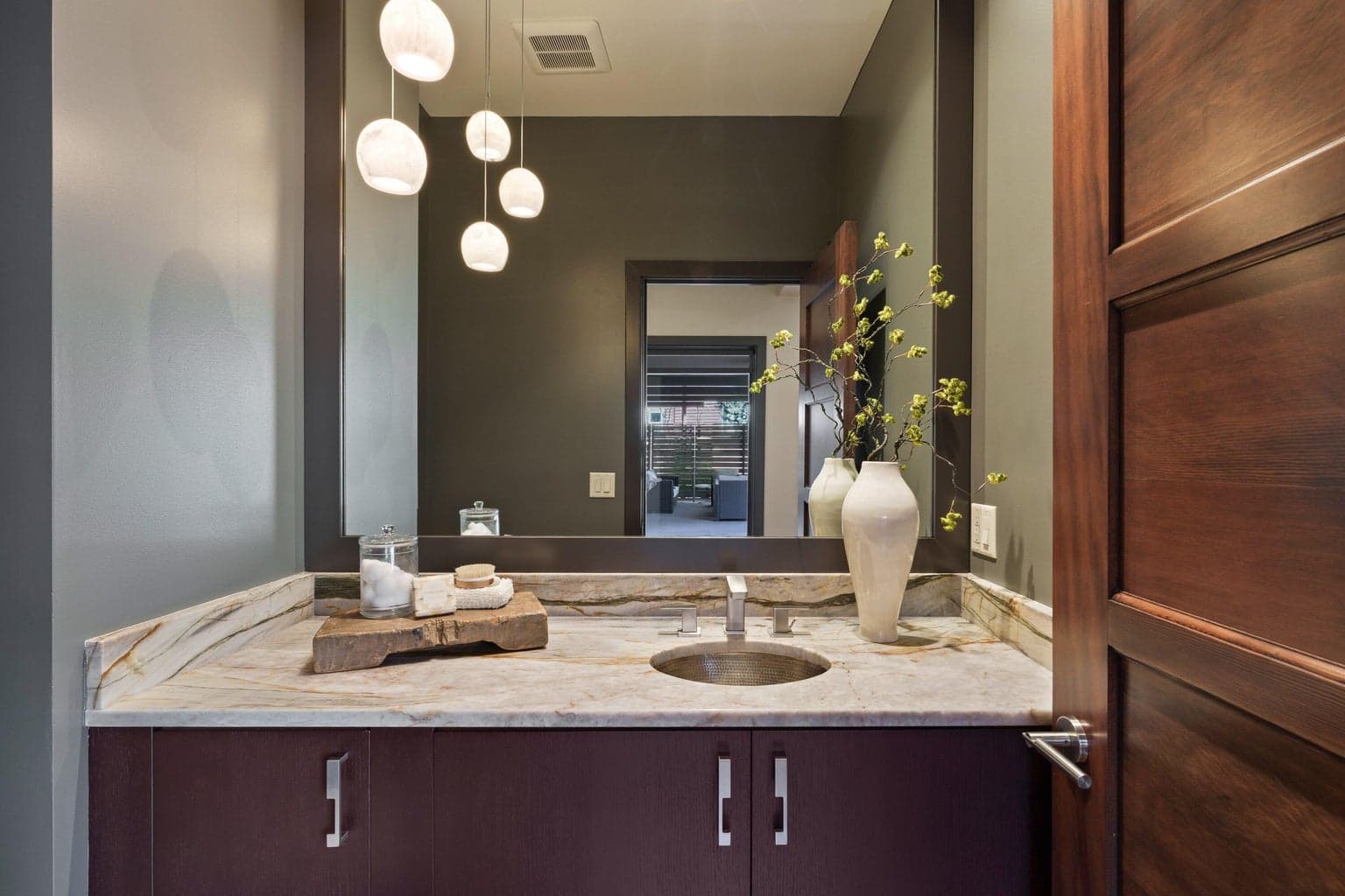Powder bath with stone countertops, modern fixtures, and warm, inviting finishes.