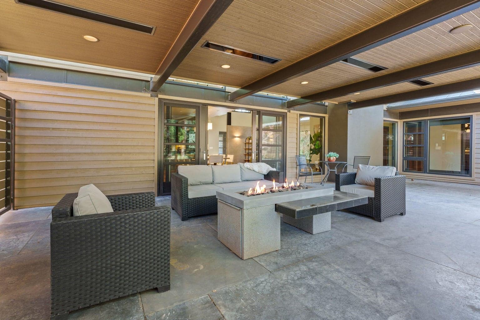 Seamless indoor-outdoor living with multiple access points, a built-in concrete fire feature, and overhead infra-red heaters—creating a comfortable, private courtyard setting for gathering in every season.