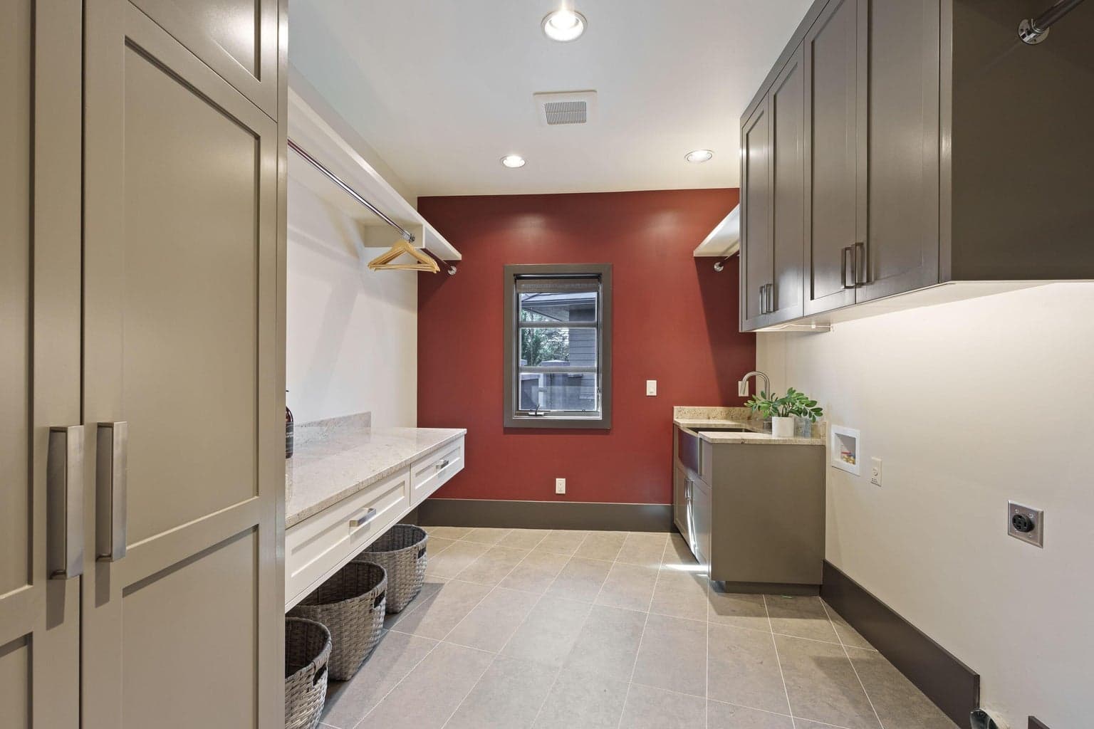 Spacious laundry room with abundant cabinetry, folding counter, utility sink, and hanging space—designed to keep everything tidy while still feeling bright and functional.