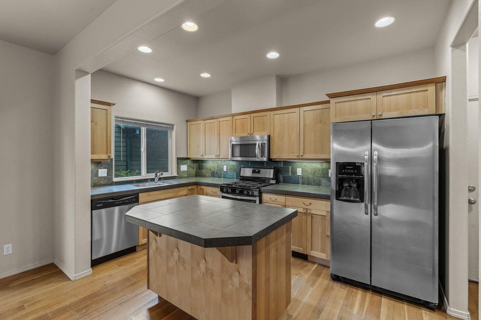 Kitchen overview showing the center island, tile counters, and breakfast bar.
