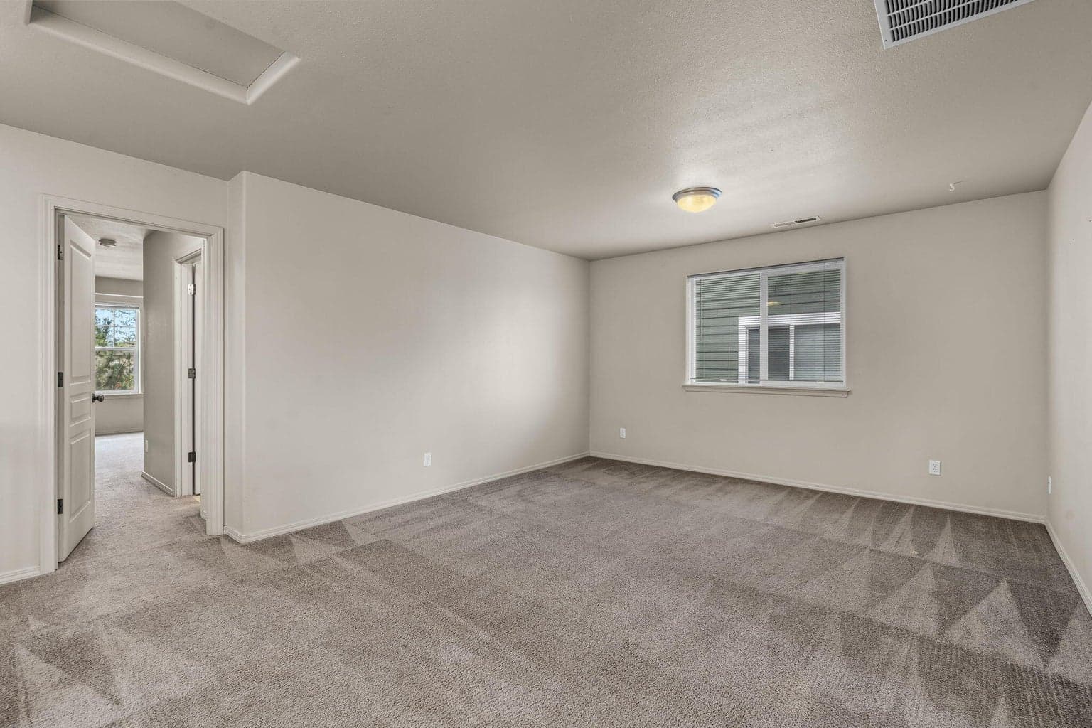 Primary bedroom suite featuring neutral colors and large windows.