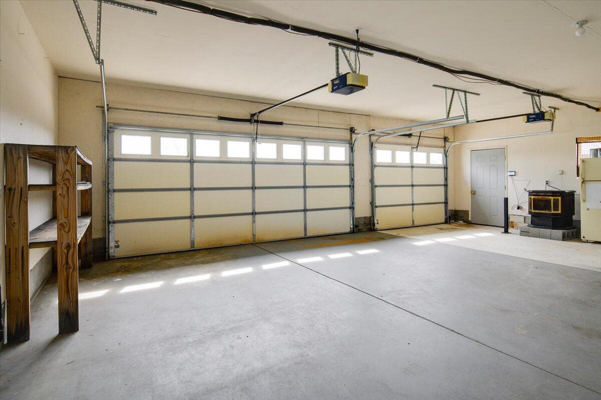 3 car garage with shelves, pellet stove, and fridge