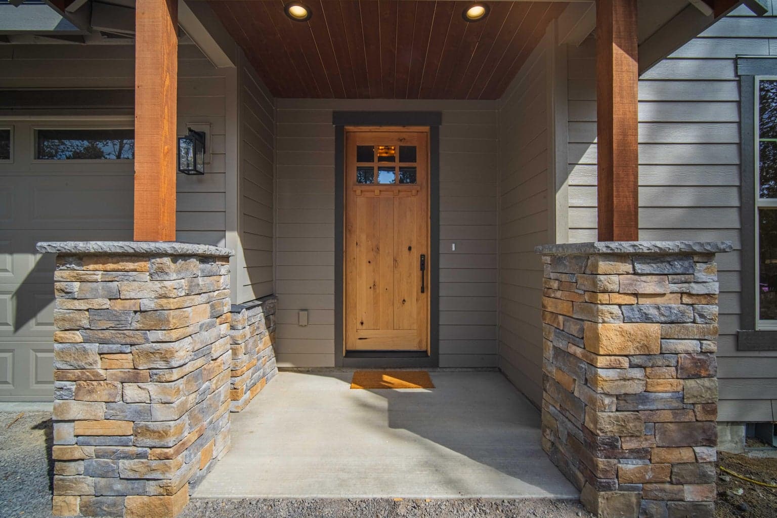 Covered front entry with stone accents, timber detail, and a custom wood door that creates a warm and inviting first impression.