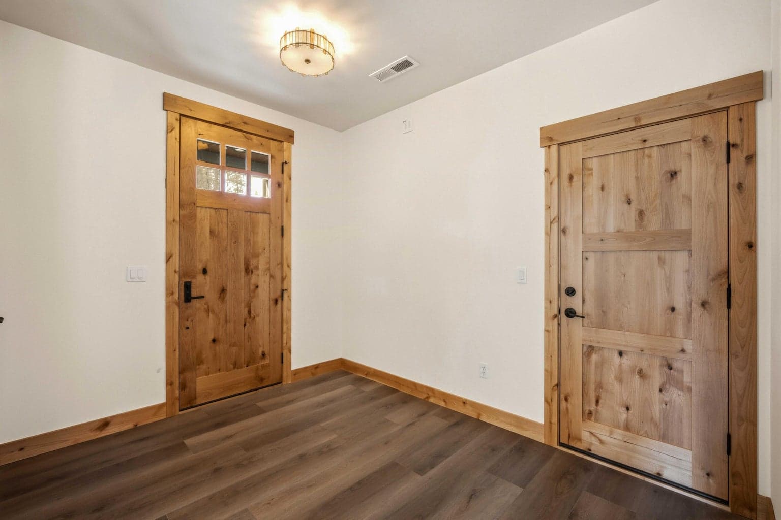 Bright entry foyer featuring rich wood trim, solid wood doors, and durable flooring for a warm, upscale welcome.