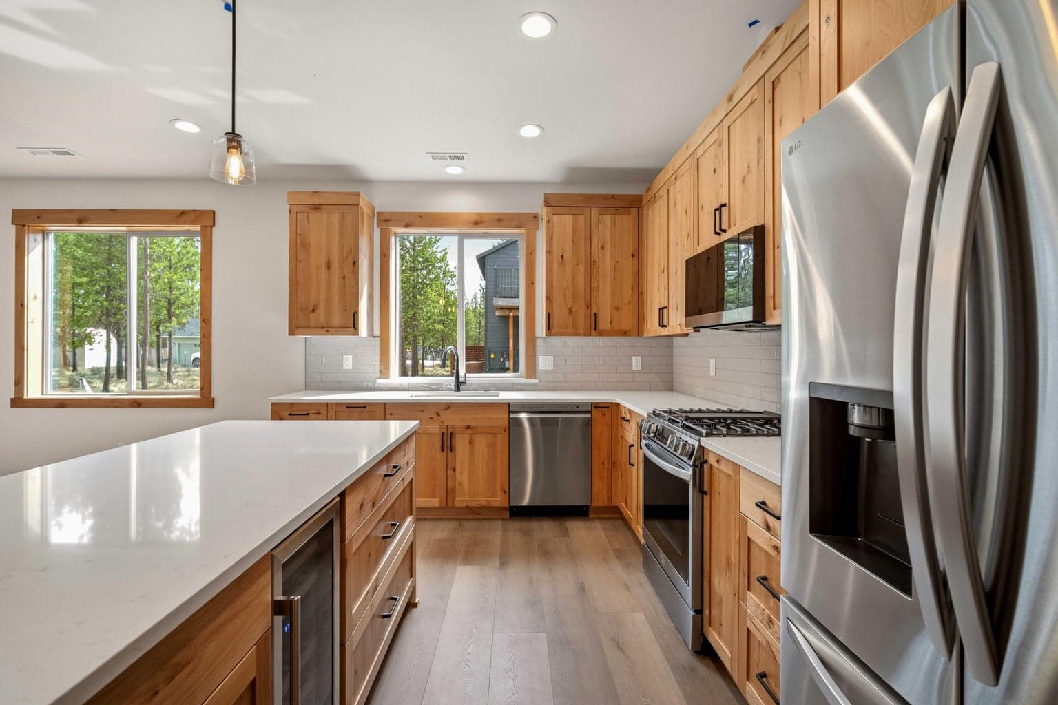 Open-concept great room and kitchen designed for everyday living and entertaining, with abundant natural light and views to the pines.