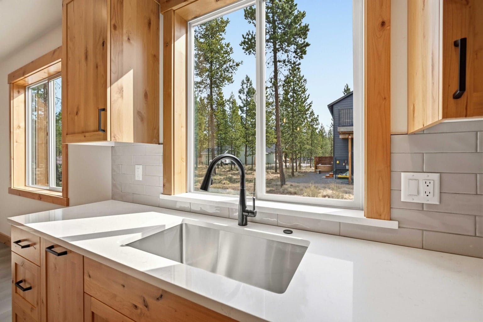 Kitchen sink window brings in natural light and peaceful pine views, adding warmth and connection to the surrounding setting.