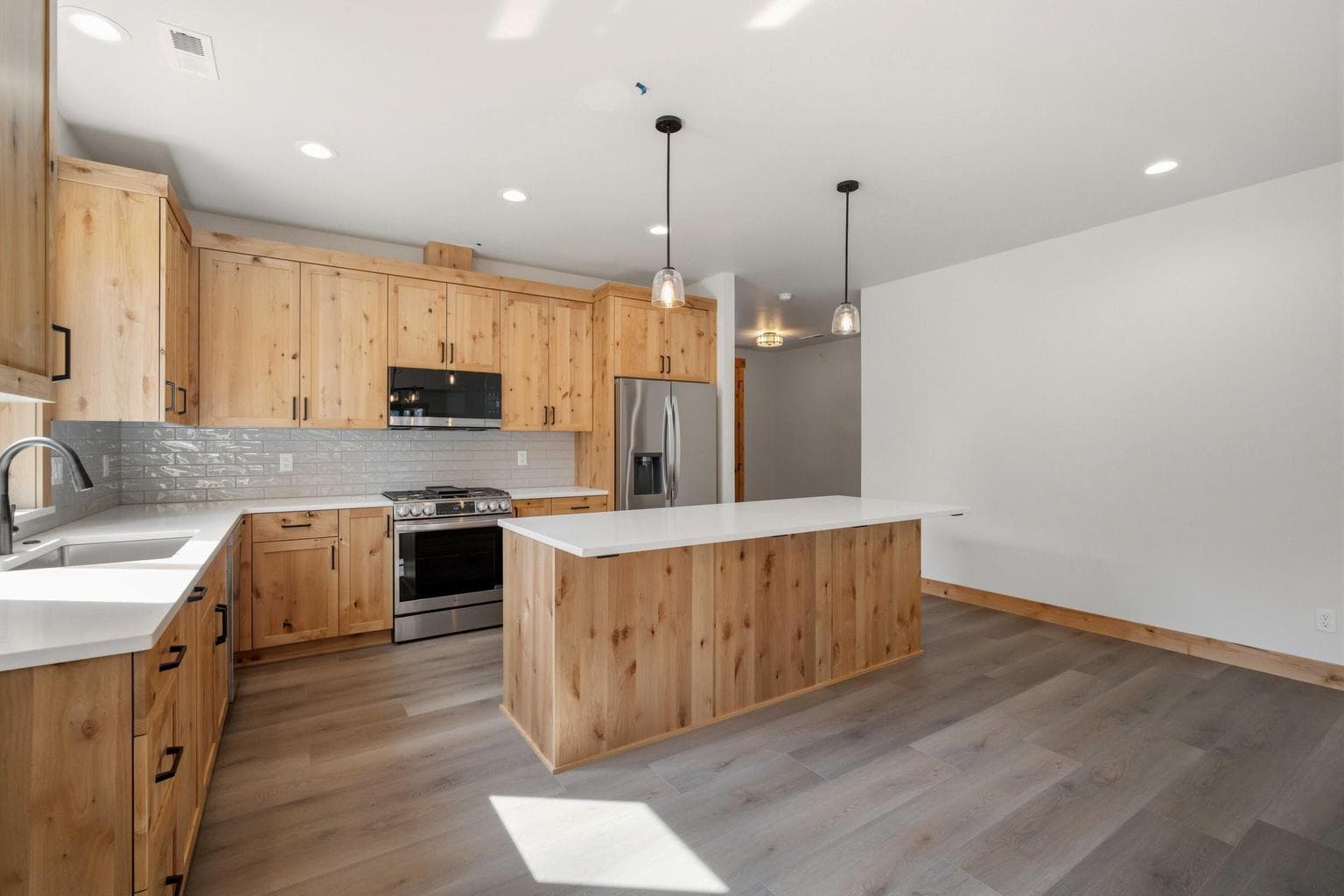 Beautiful open kitchen with warm wood cabinetry, quartz surfaces, and a generous island designed for both style and function.