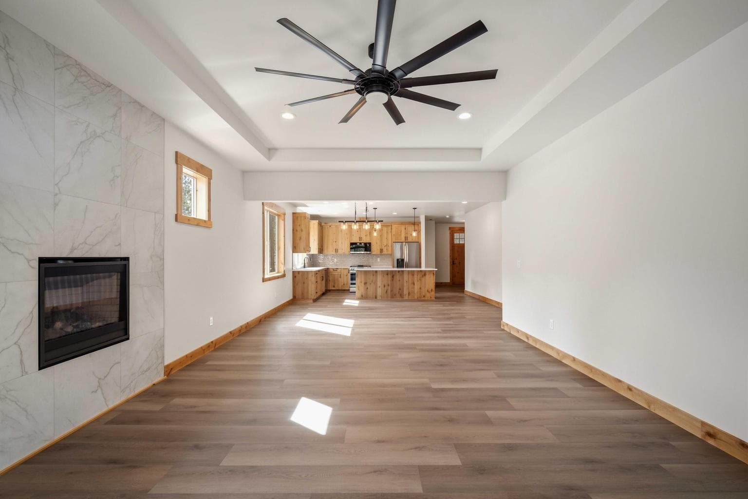 Spacious open-concept living area with a dramatic ceiling fan, fireplace feature, and easy connection to the kitchen and dining spaces.