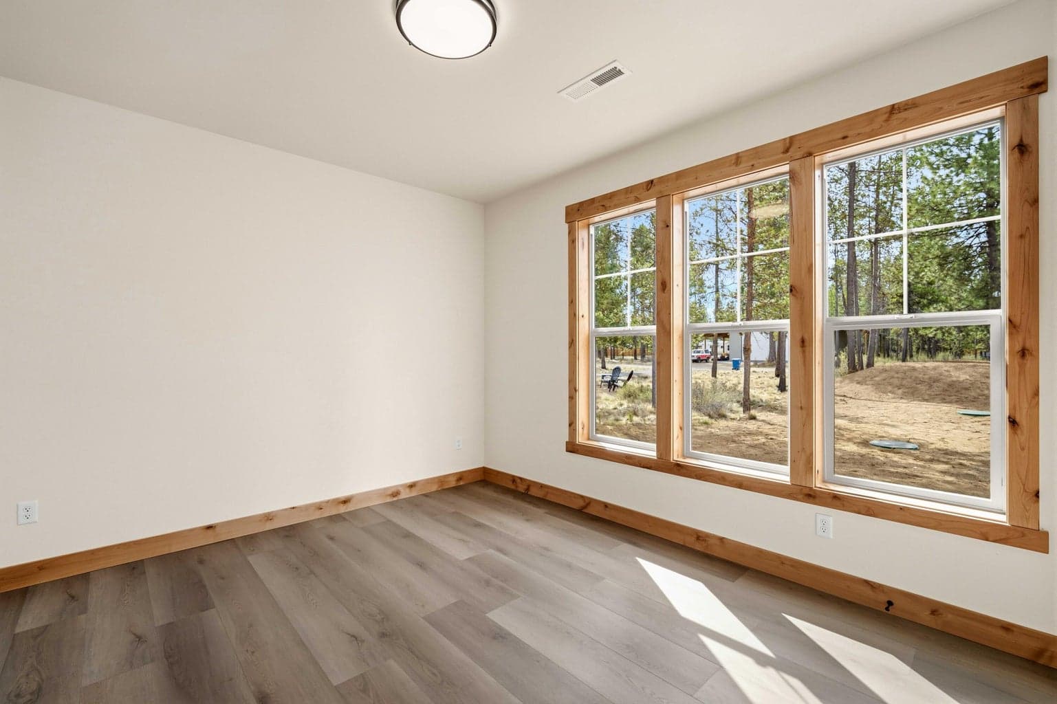 Flexible office or fourth bedroom with durable hard-surface flooring, abundant natural light, and views to the surrounding pines.