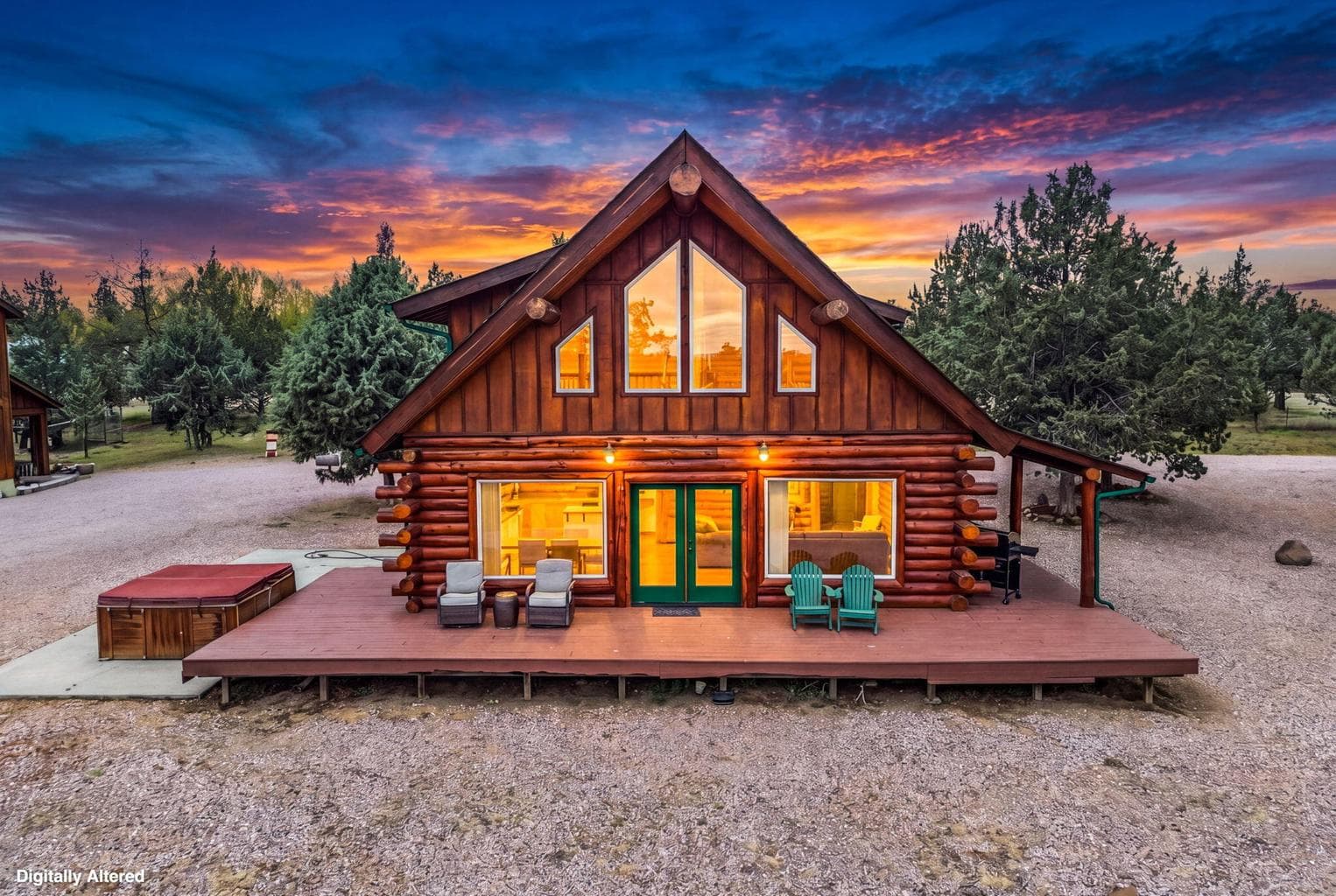 Front view of the two-story hand-hewn log home with a large covered porch in a sunset setting.