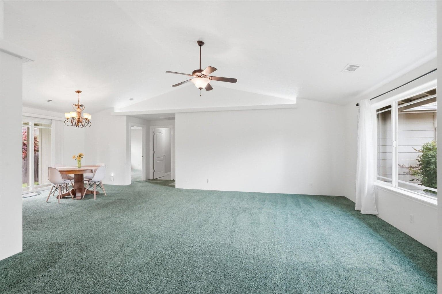 Living room with vaulted ceiling, picture window, and clean cushy carpeting
