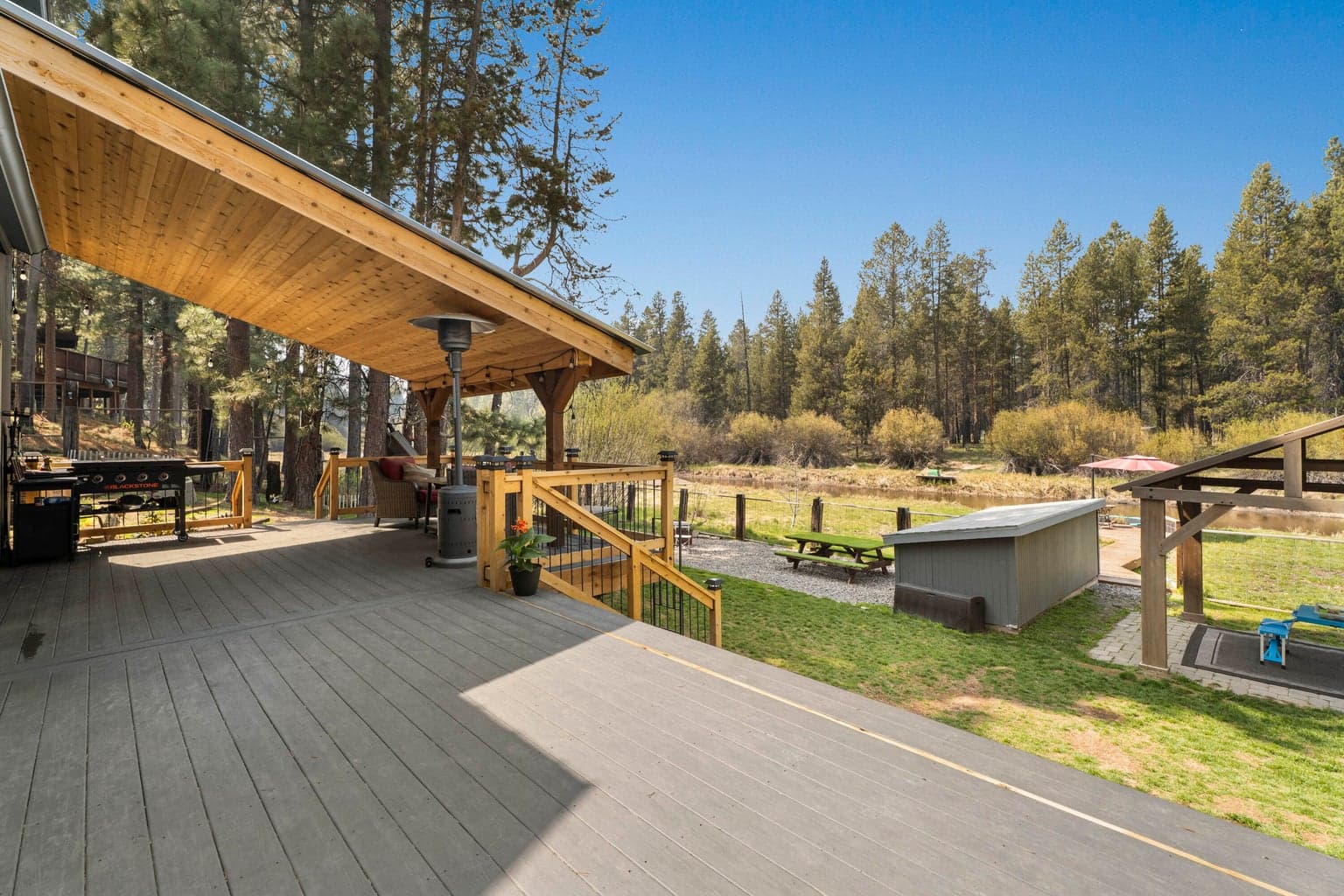 Grilling deck steps down to the lawn, pavilion, and water beyond