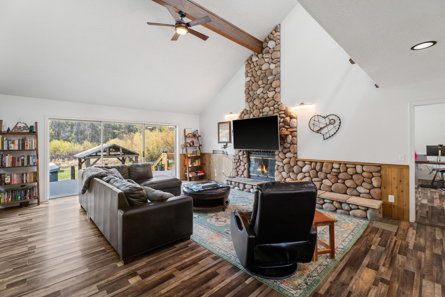 Living room reveal from the loft with vaulted ceilings and floor-to-ceiling river-rock fireplace