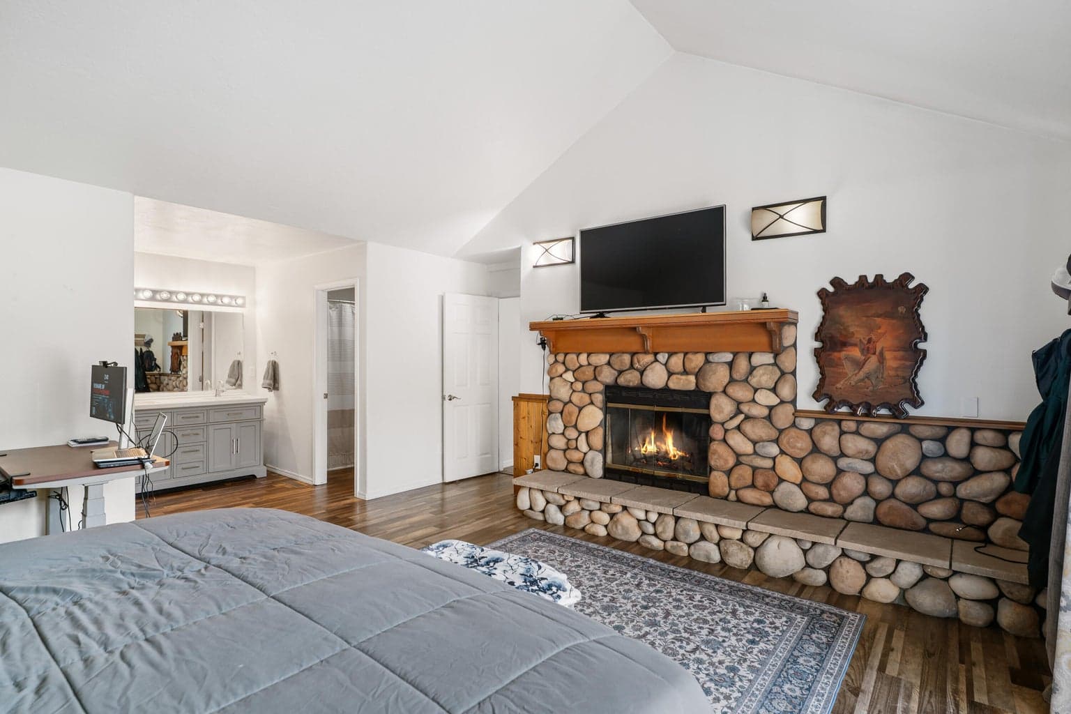 Primary suite with private river-rock fireplace and en-suite vanity