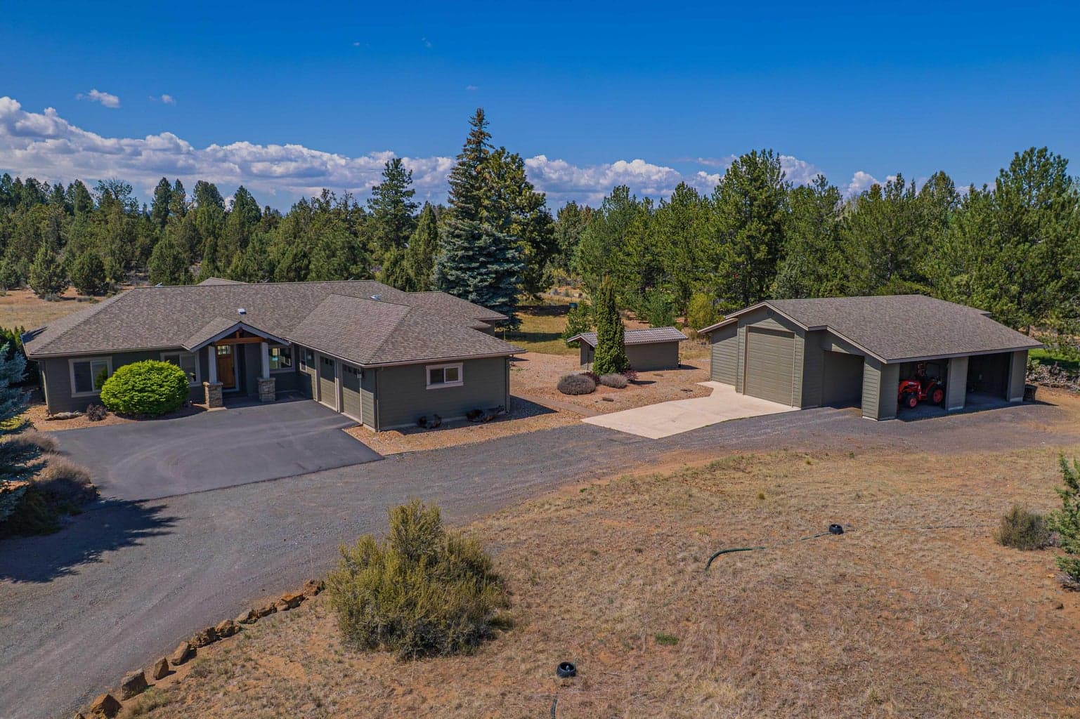 Custom single-level home with detached RV barn/shop, open drive areas, natural landscaping, and a quiet treed north Bend acreage setting.