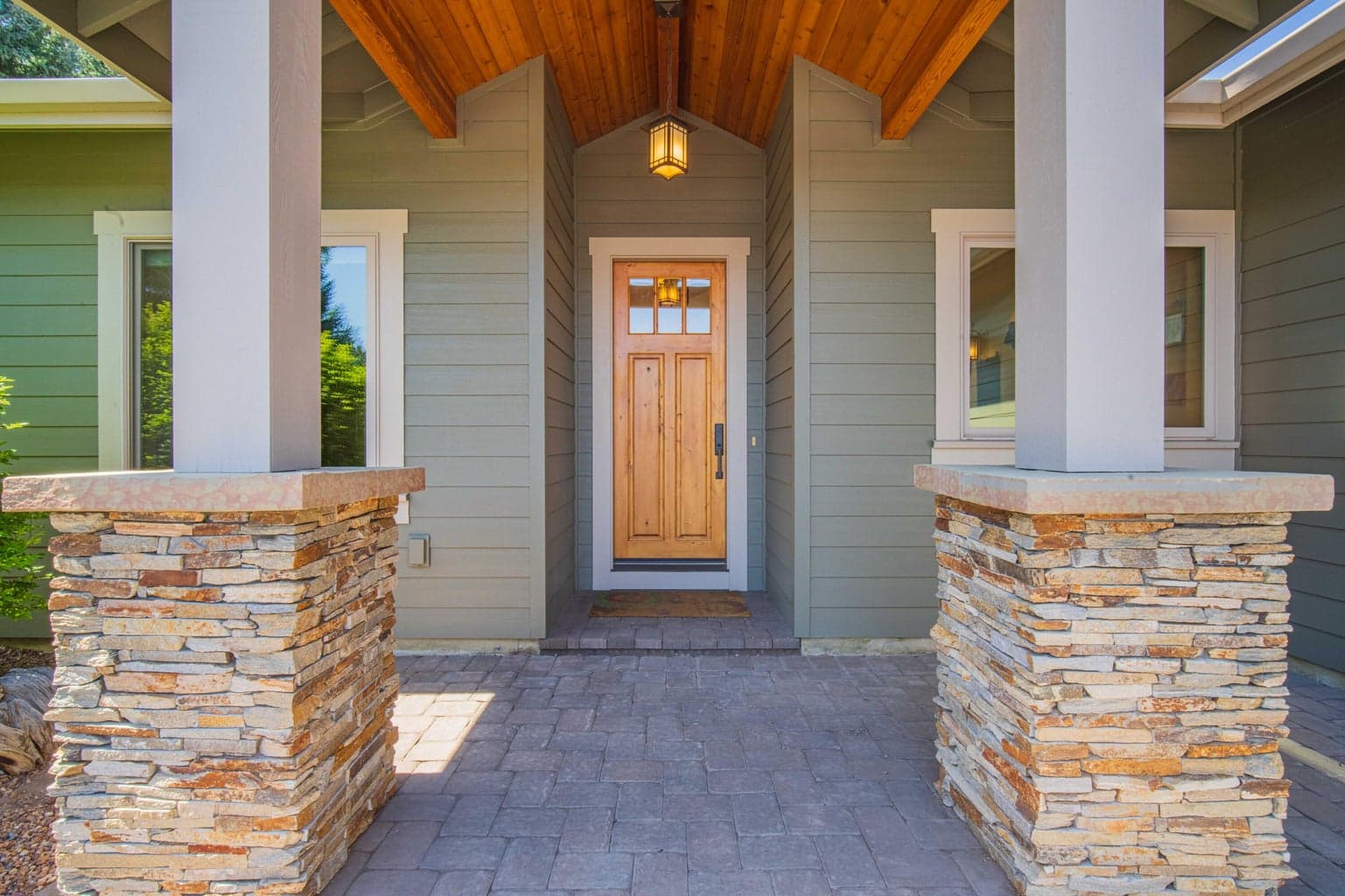 Covered front entry with wood ceiling detail, stone accents, and a warm custom-home arrival.