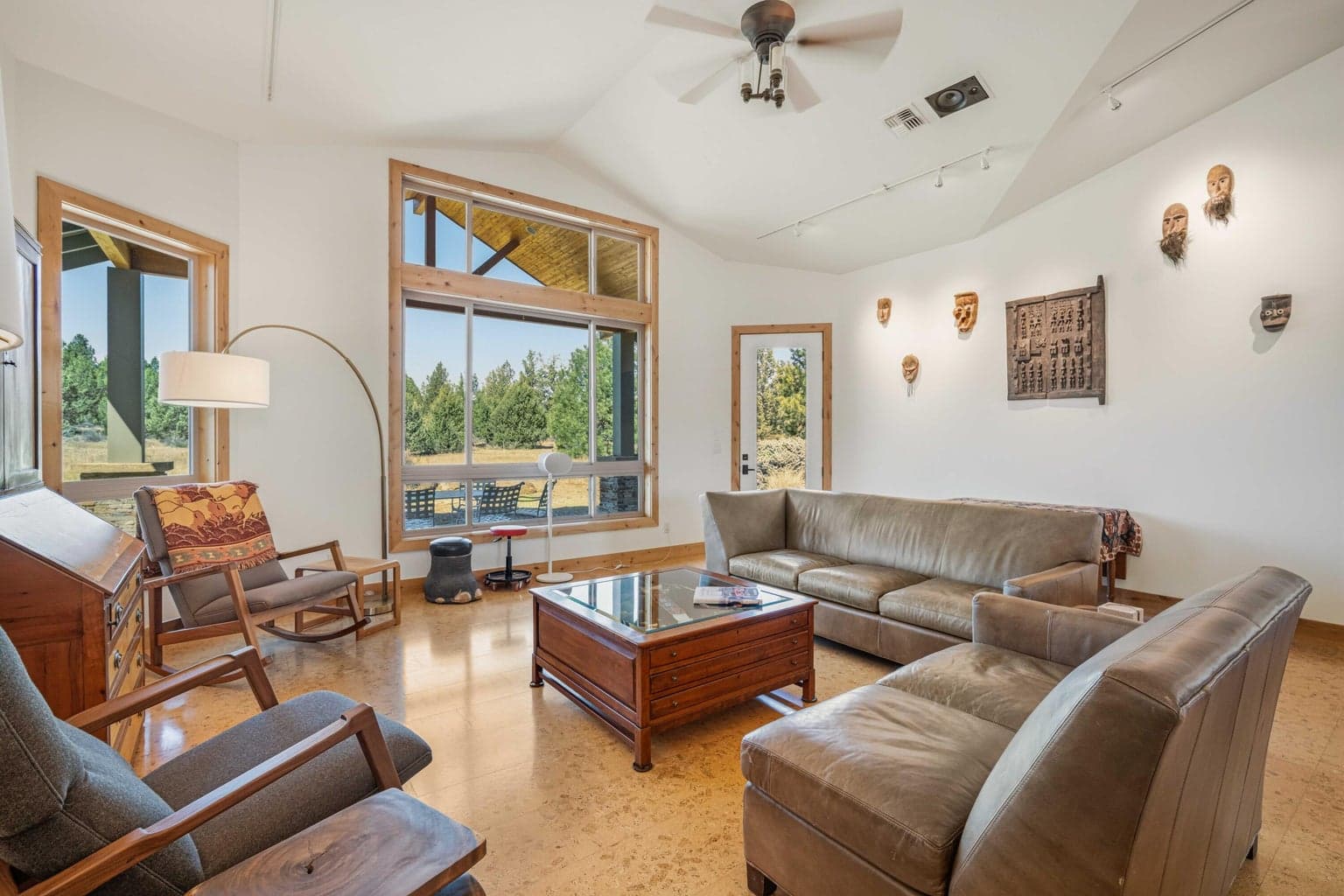 Light-filled living room with vaulted ceiling, large windows, and natural views toward the acreage setting.
